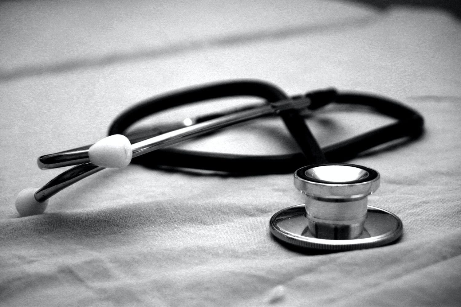 Greyscale photograph of a stethoscope on a desk